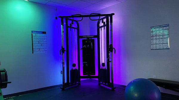 Cable machine with colorful lighting shining behind it.