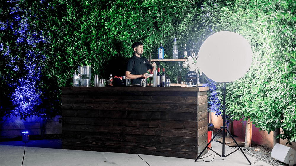 Man at residential outdoor bar and Feit Electric LED Inflatable Balloon Light next to the bar.